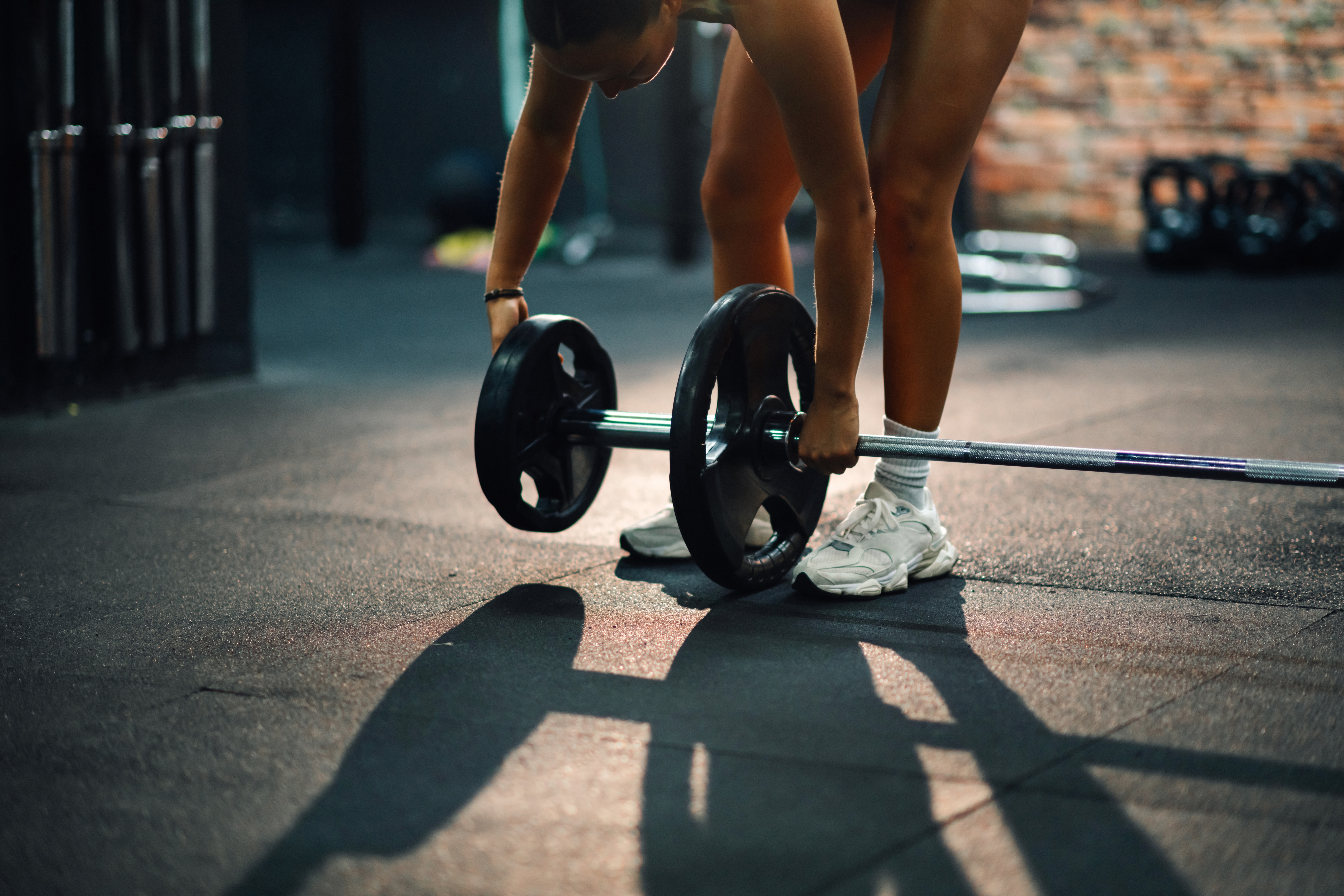 Young,Woman,Is,Adding,Weights,To,A,Barbell,,Preparing,For
